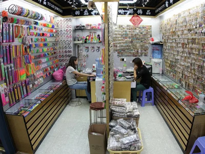 Wholesale market stalls with densely packed product shelves and jewellery displays.