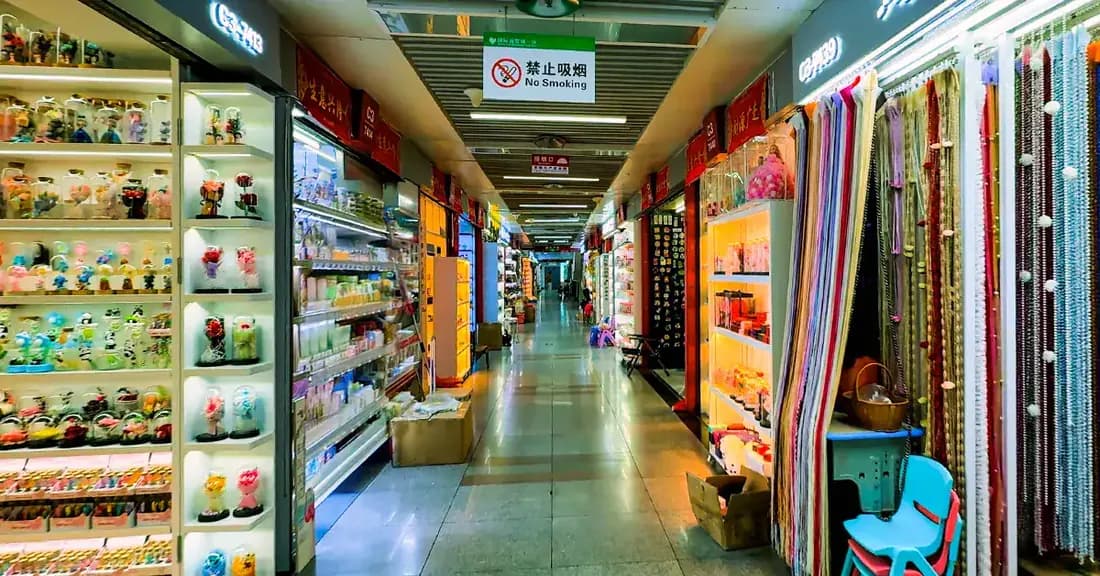 Indoor wholesale market corridor lined with supplier showrooms and product displays.
